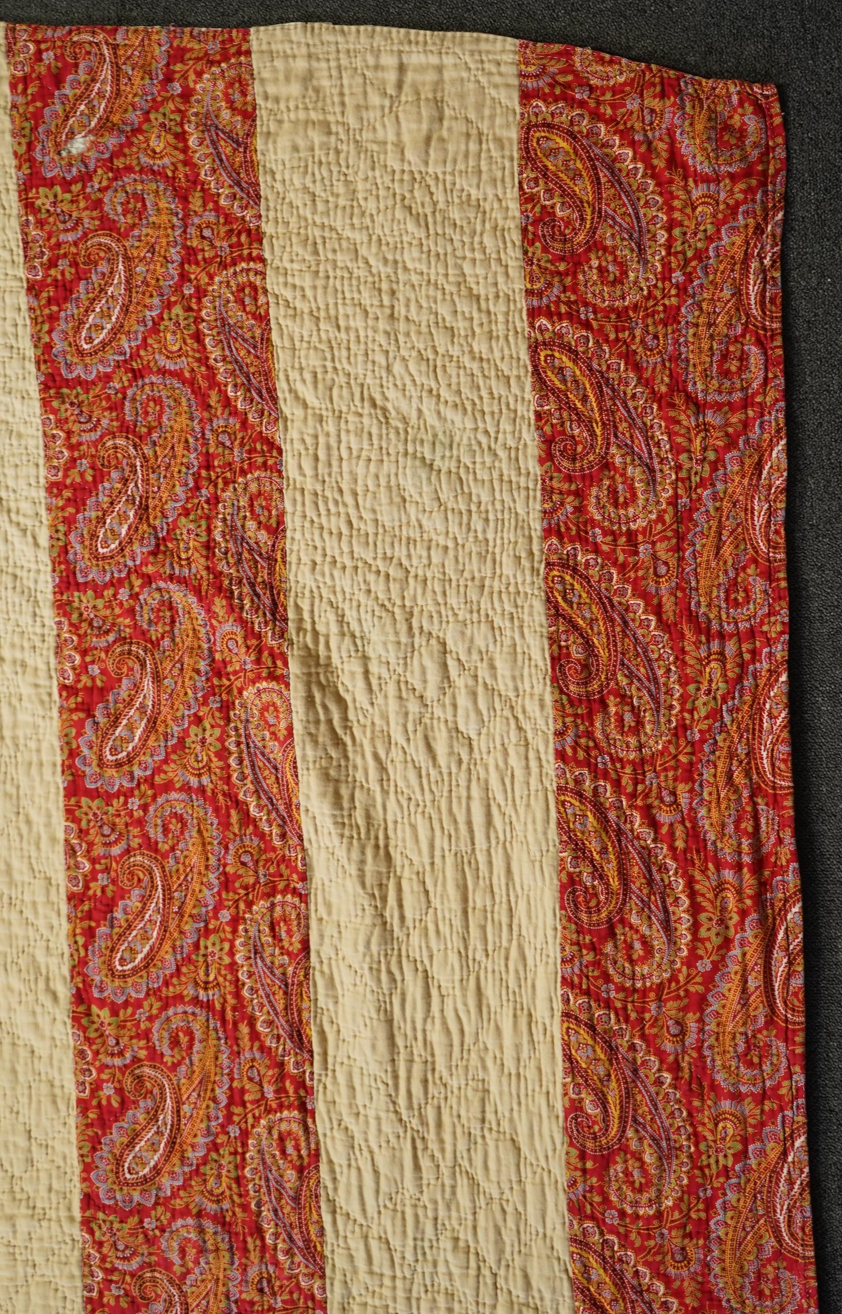 An English cotton hexagon hand made and hand pieced quilt, made from a large variety of printed dress fabrics from 19th century. The quilt edged with a wide stripped multi fabric border. The under side designed in wide s